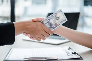 photo of Businessmen shakes hands and dollar note, sign a contract to bribe corruption in the company. The concept of bribery and corruption