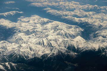 Fototapeta premium View from airplane on Earth surface - snow-capped mountains.