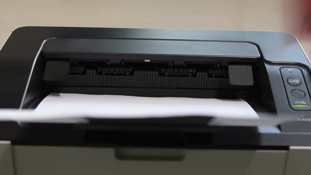 Closeup of laser printer.  Blurred hand turns one sheet of paper over to reveal word SUCCESS. 