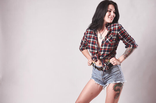 Tattooed brunette in plaid shirt on gray background