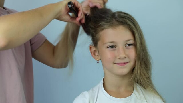 Young gerl getting her hair dressed . mother combing hair comb girl blonde. 4K.