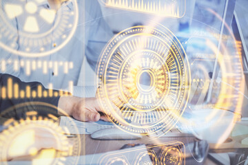 Technology theme hologram with man working on computer on background. High tech concept. Multi exposure.