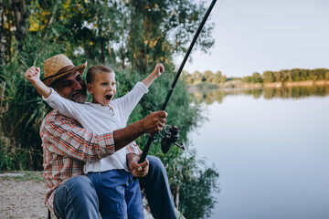 grandfather and grandson fishing outdoor on the lake, little boy looking at the camera
