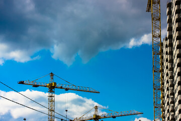 Glass facade of a modern building in a big city: a construction crane against a blue sky.