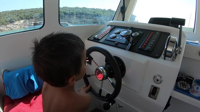 Child steering the rudder in the boat. Learning to ride a boat.