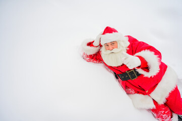Happy santa claus lying in the snow and fooling around