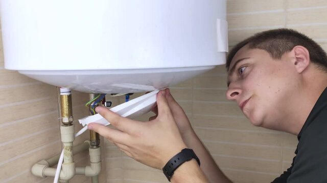A locksmith fixes a boiler that is not working. The worker will check the electronics and unscrew the nut on the pipe with an adjustable wrench. Technical assistance concept