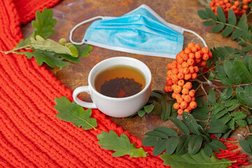 Beautifully designed still life, layout, red scarf, green oak leaves, acorns, apples and a medical mask. Concept, autumn has come, protect yourself during coronavirus, quarantine,