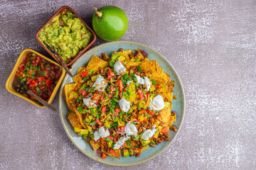 Loaded minced pork nachos with guacamole and salsa dips