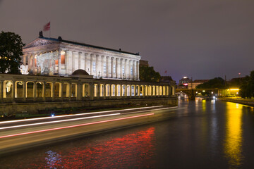 The Alte Nationalgalerie (Old National Gallery) photographed at night. Long exposure photography shows light streaks of boats