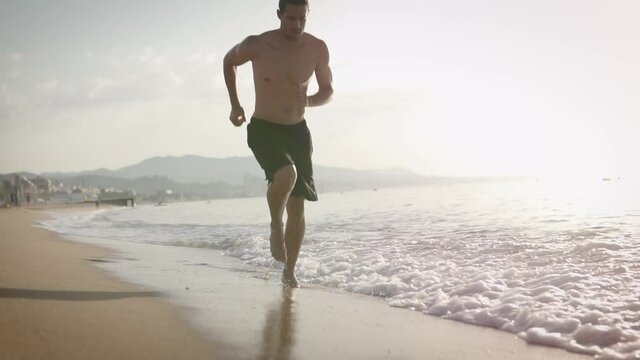 Fitness Male running at the beah at sunrise. Summer workout outdoors. Fit man doing exercise in the morning. Healthy lifestyle. Sports coach training alone