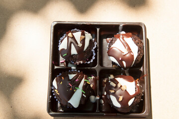 This dark brown brownie topped with chocolate and nuts makes it even more appetizing on the light brown wood floor, shot in the morning in natural light from above.