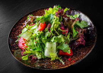 various fresh mix salad leaves with tomato, cucumber and red pepper on a plate