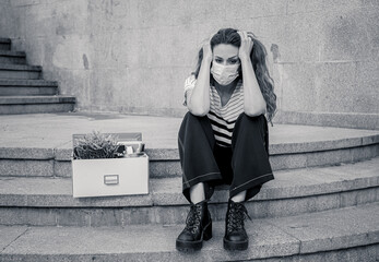 Sad woman sitting outside office feeling hopeless after being fired. Coronavirus job cuts crisis