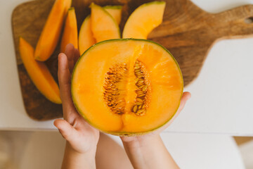 Cute beautiful little boy eating fresh melon. Healthy food, childhood and development. 