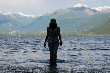 Woman Standing in a Flooding Alpine Lake with Snow-capped Mountain in Locarno, Switzerland.