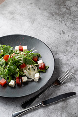 Fresh summer salad in a restaurant for those who are on diet: rucola, ripe potatoes, feta cheese, top view