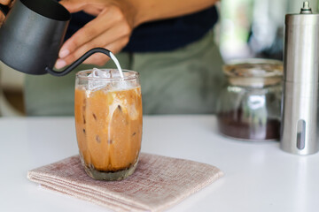 Close up professional of a barista poured milk-making iced coffee with equipment, tool brewing on the bar at kitchen home