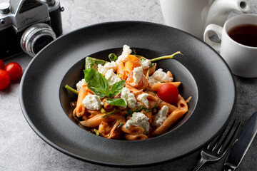 Gourmet penne pasta with cherry tomatoes and goat cheese, top view, close up