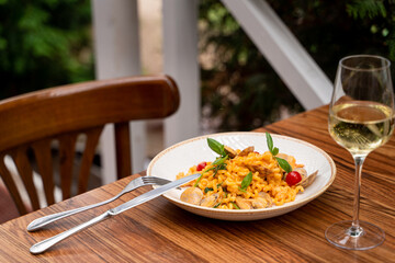 Restaurant terrace with wooden table: seafood pasta with mussels and a glass of a good white wine