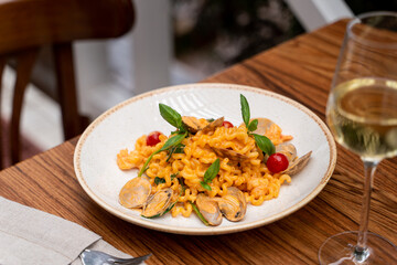 Seafood creamy pasta on a terrace wooden table, wine glass and fork aside
