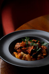 Close up of pork and potato stew in a dark posh restaurant