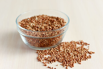 Raw buckwheat groats in a transparent glass plate on wooden