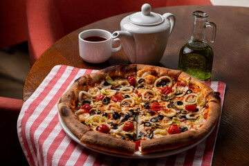 Italian pizza with thick dough crust, olives and onion on a wooden table