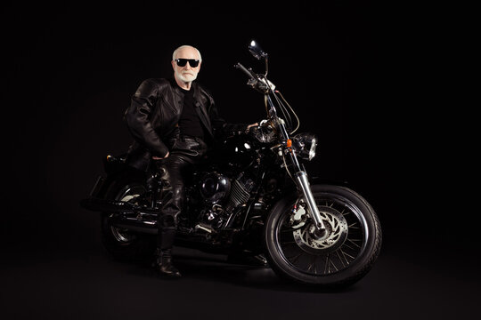 Portrait of his he nice attractive cool content grey-haired guy hipster traveler sitting on chopper having fun weekend vacation holiday tour trip chill isolated black color background