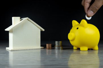 Pig piggy bank Saving coins for a real estate project with miniature houses and a pile of coins. (The concept of saving money And real estate)