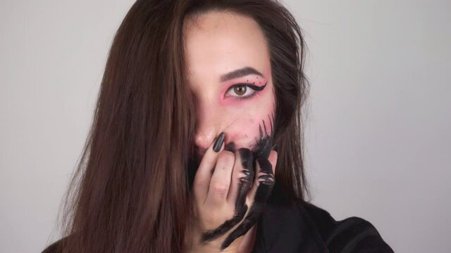 Sexy woman smears paint all over her face. Woman washing off makeup for halloween. High quality 4k footage