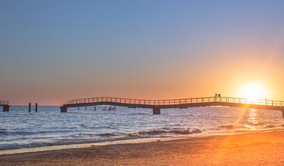 Fototapeta premium An impeccably beautiful sunset on the sea. Sunset against the backdrop of a ruined maritime dock: an idea of ​​the passing time and the need for change.