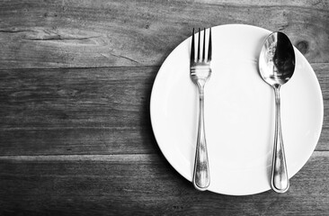 White plates, spoon and fork tableware (Vintage concept, black and white photo)