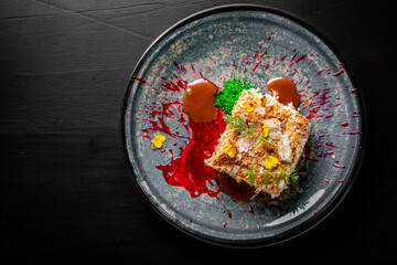 Layered cake with cream Napoleon in plate on wooden table background