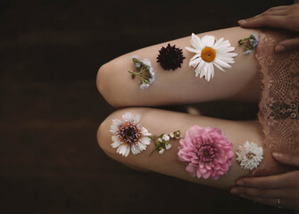 Wild multi coloured flowers lying on the legs of a young woman. Spa and beauty concept