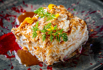 Layered cake with cream Napoleon in plate on wooden table background