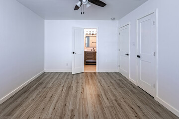 Empty bedroom with open doors leading to the livingroom, bathroom and a closet