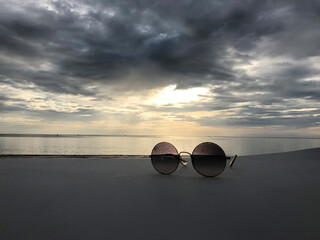 Fototapeta na wymiar Sunglasses on sunset sky view background