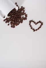 Coffee beans spill out of the cup on white background. Coffee heart