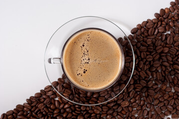 Top down view of coffee cup and fresh coffee beans on white background.