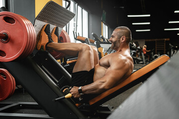 Bodybuilder doing a seated leg press exercise in a gym