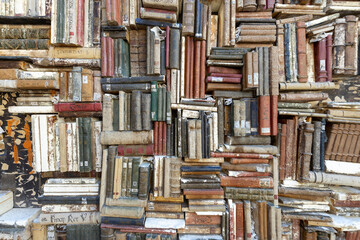 old books piled on a wall, stacked in a disorderly fashion