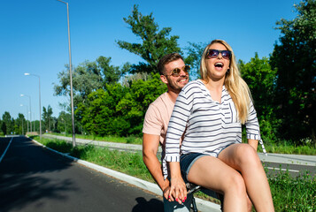 Obraz premium Cheerful young couple having fun riding on bicycle on summer day.