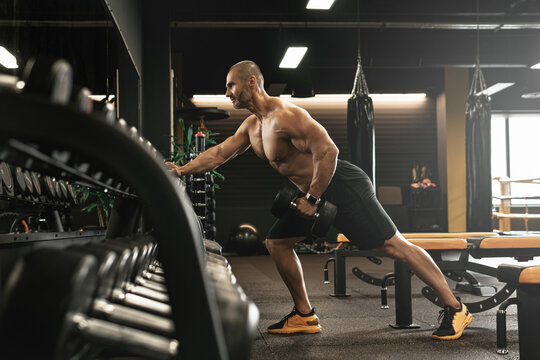 Bodybuilder doing one-arm dumbbell row during his workout in a gym