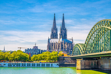 Fototapeta premium Cologne cityscape of historical city centre with Cologne Cathedral Roman Catholic Church of Saint Peter gothic style building, Hohenzollern Bridge across Rhine river, North Rhine-Westphalia, Germany