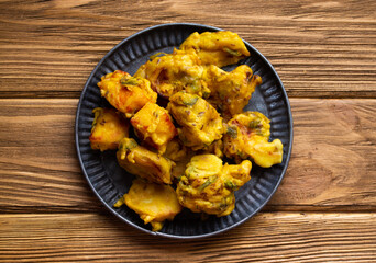 Indian fried assorted pakoras on wooden rustic background. Traditional Indian mixed vegetable crispy fritters, snack or appetizer. Top view.