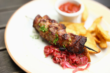 On plate there is kebab potato salad and there is ketchup next to it. Lunch menu concept