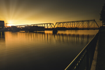 sun is setting behind the bridge ahead in the golden hour