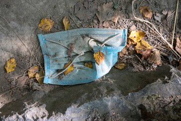 Fototapeta na wymiar Used disposable mask is thrown to the ground