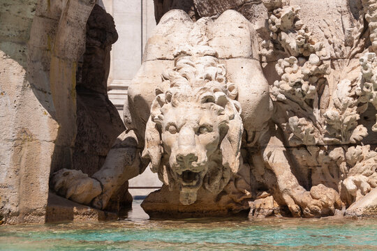 Statue of a menacing lion, drinking water at the Fountain of the Four Rivers, Piazza Navona, Rome.